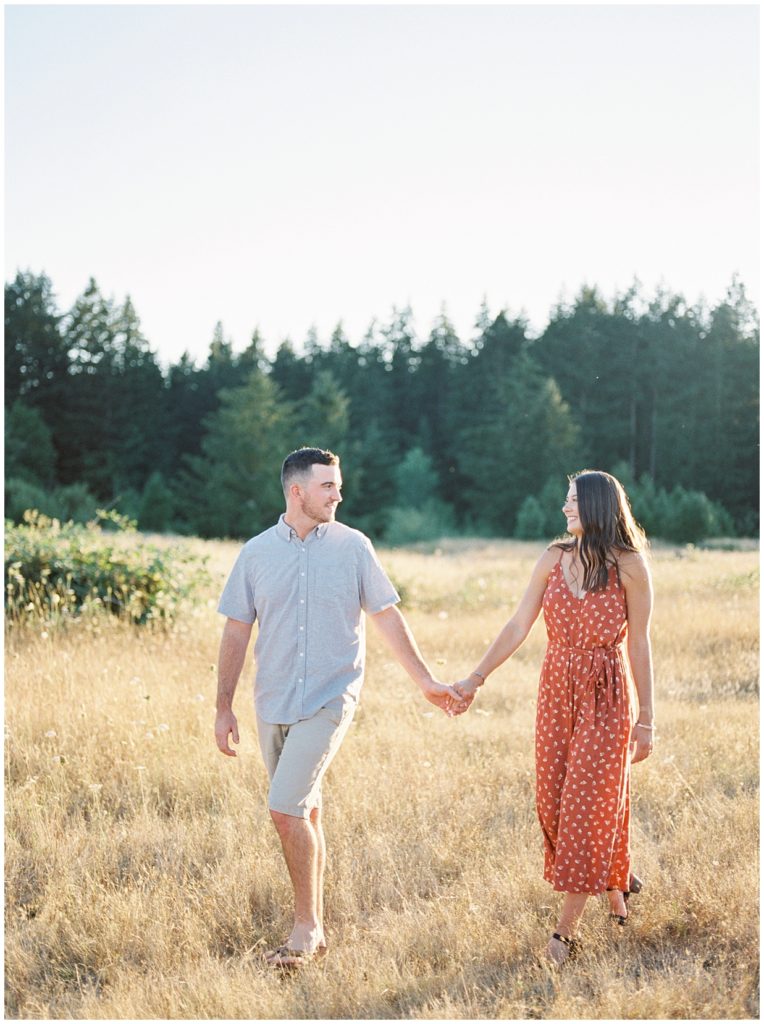 Couple holding hands walking in field