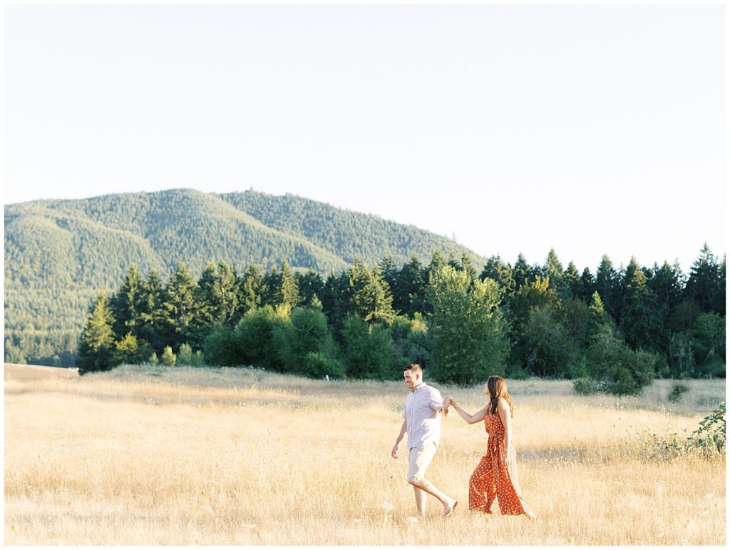 Engaged couple walking through field