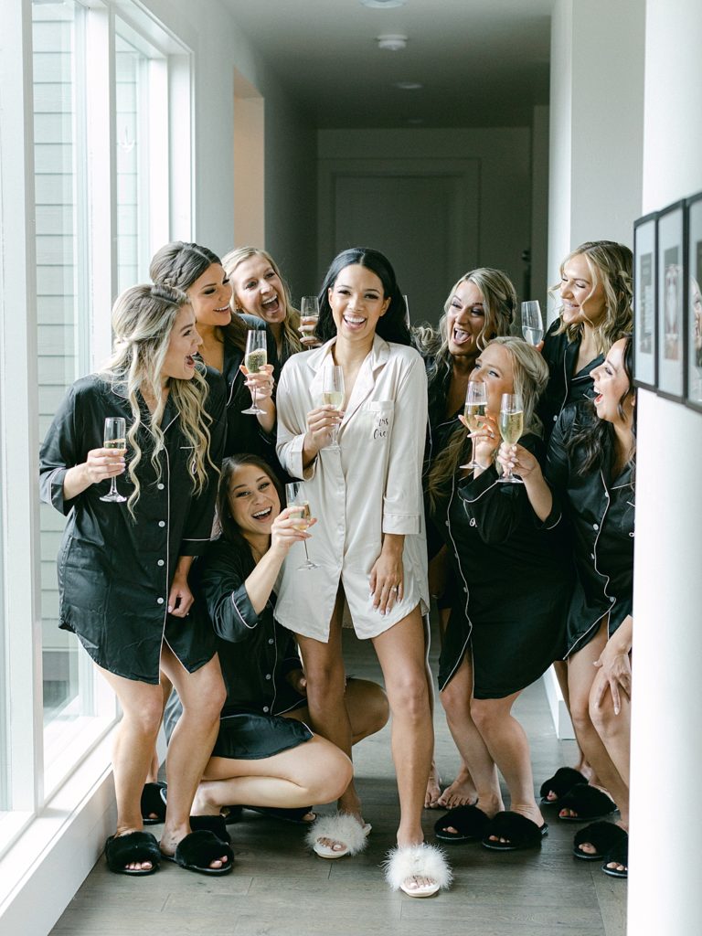 Chic and modern wedding - Bride and bridesmaids in pajamas toasting with champagne