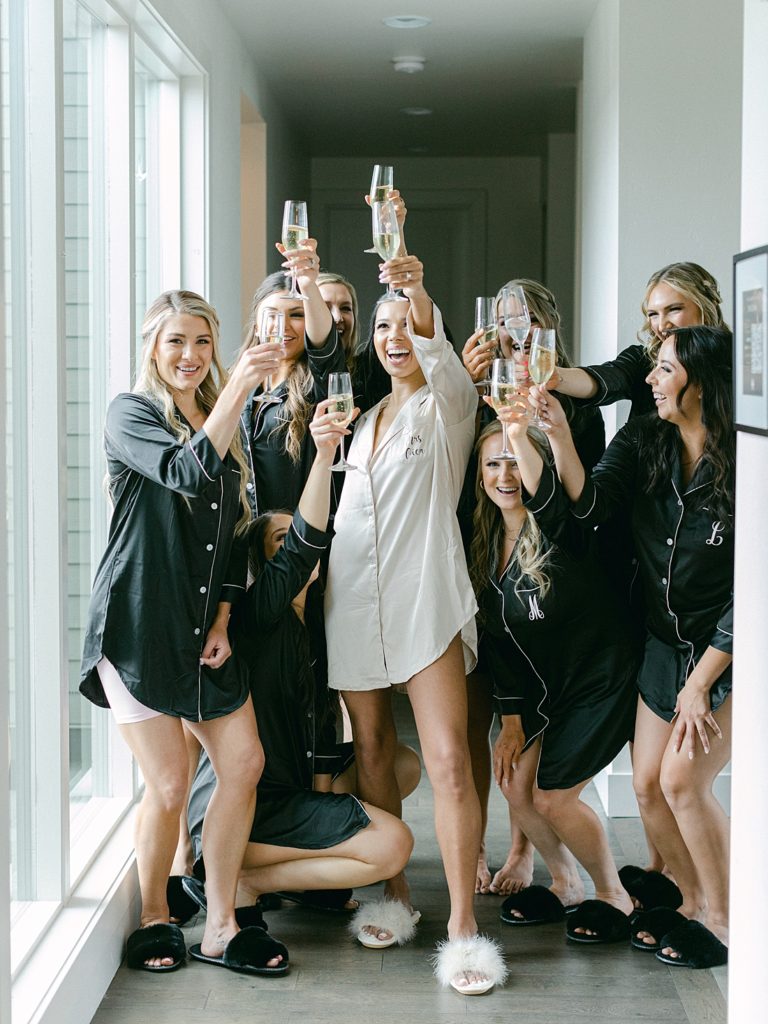 Chic and modern wedding - Bride and bridesmaids in pajamas toasting with champagne