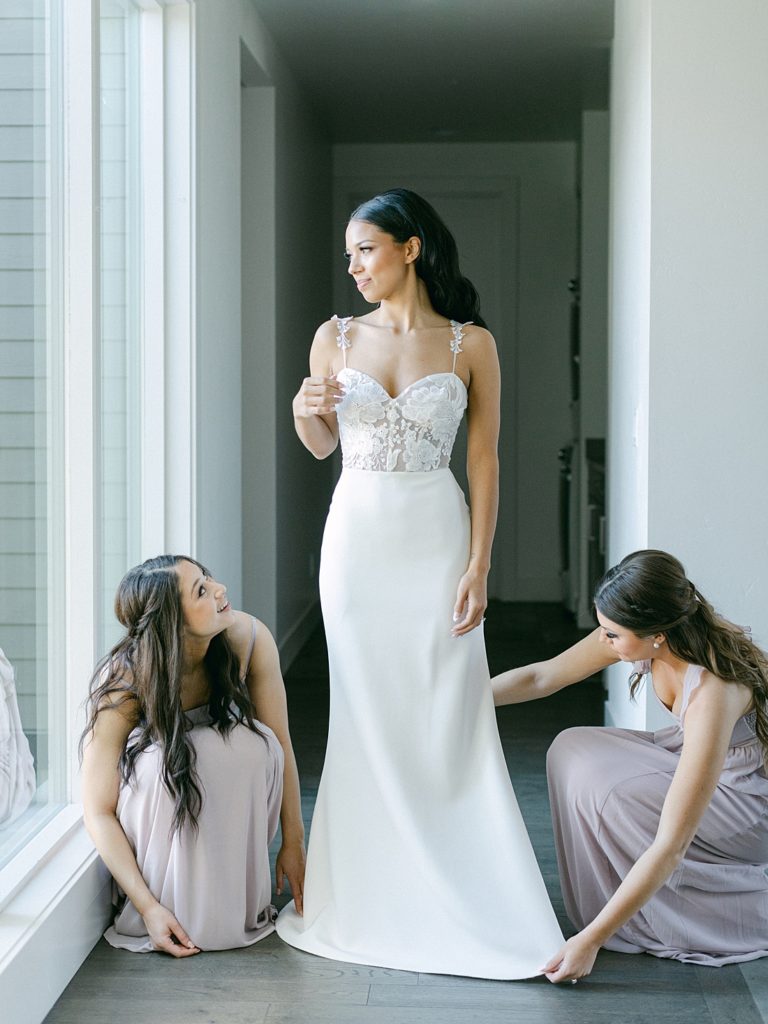 Chic and modern wedding - Bridesmaids helping bride into dress