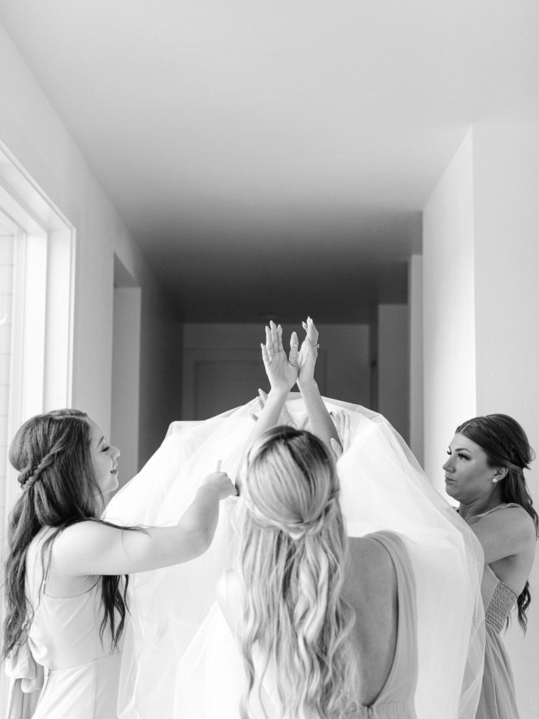 Bride getting into dress with help from her bridesmaids