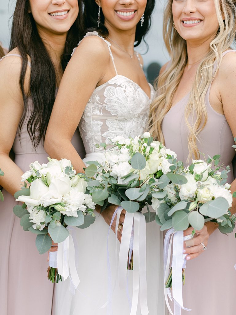 Bride and bridesmaids with bouquets of white flowers and greenery