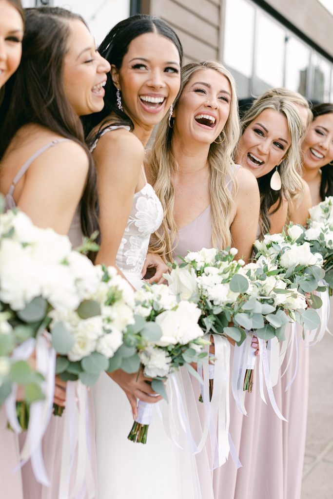 Bride and bridesmaids with bouquets of white flowers and greenery