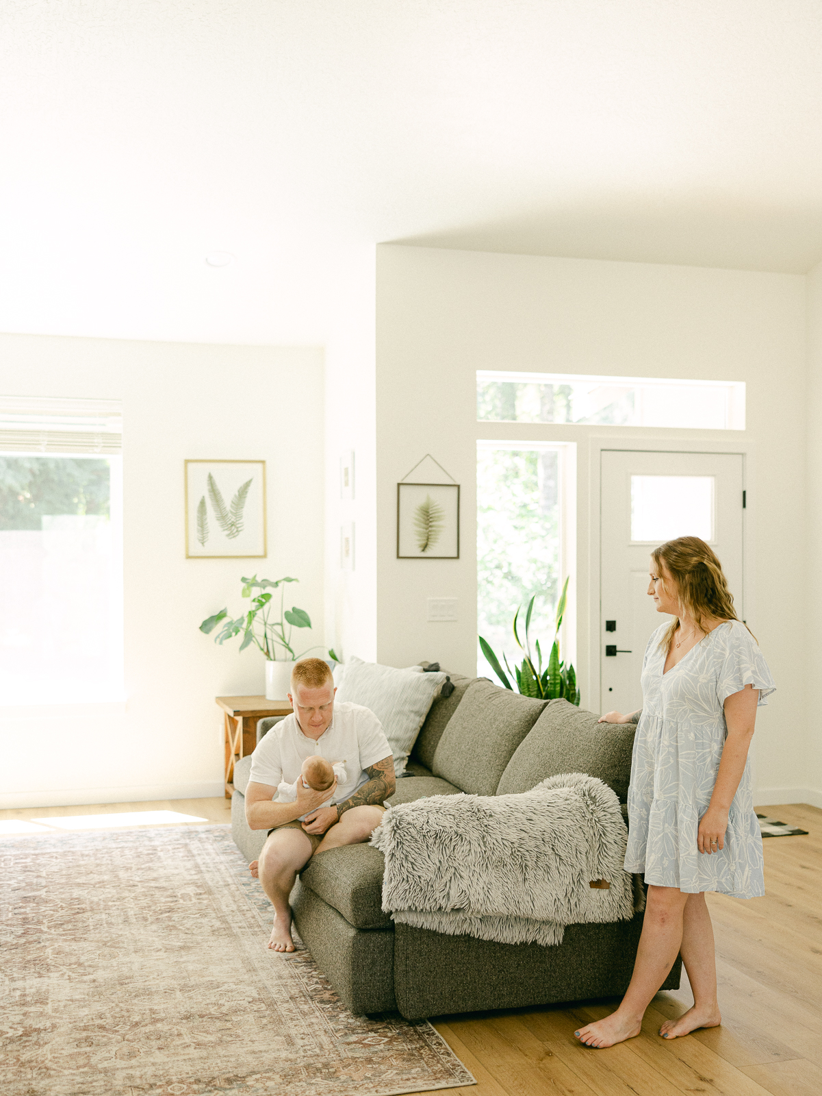 a man and woman standing in a living room with a baby