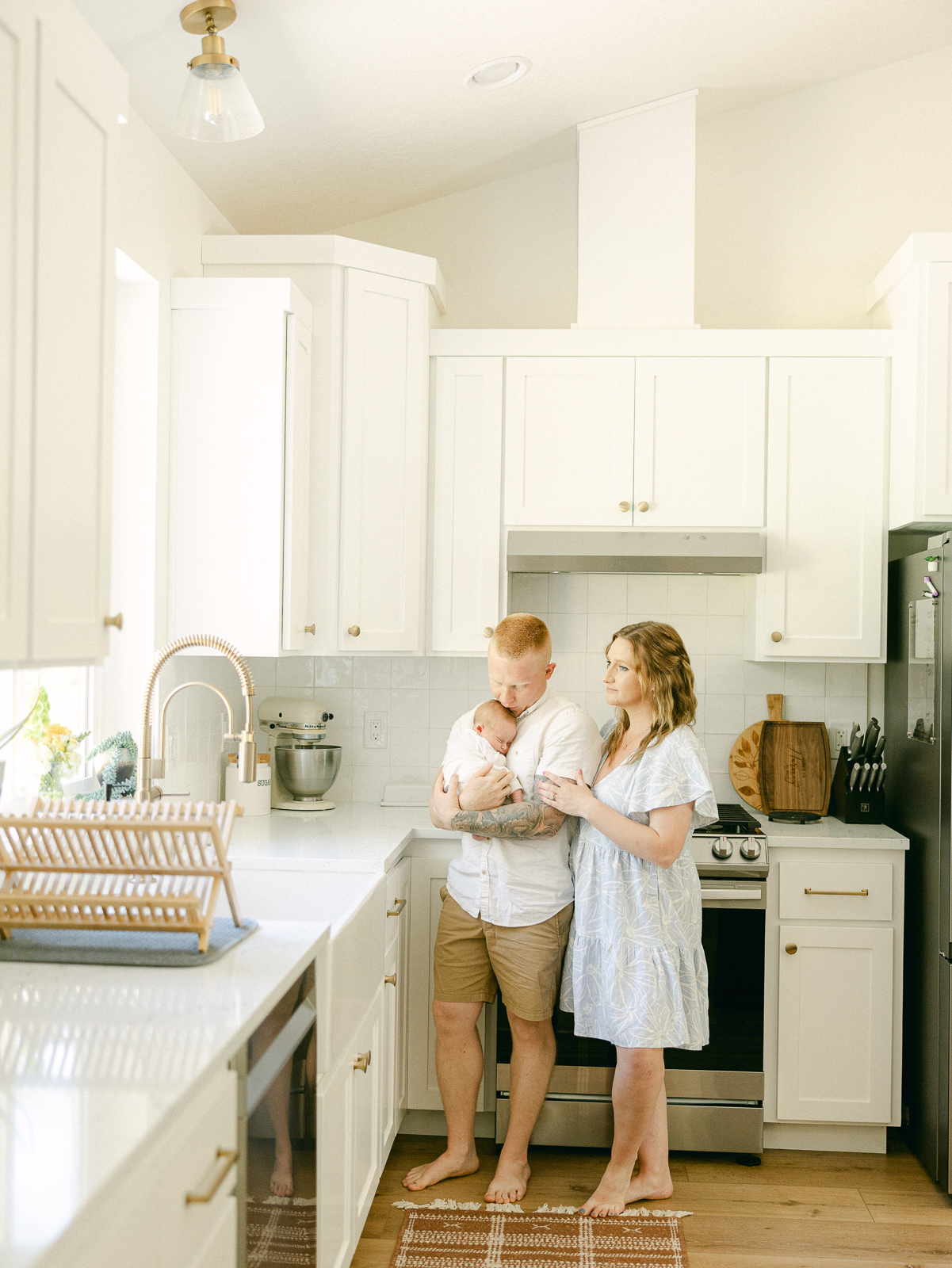 a man and woman holding a baby in a kitchen