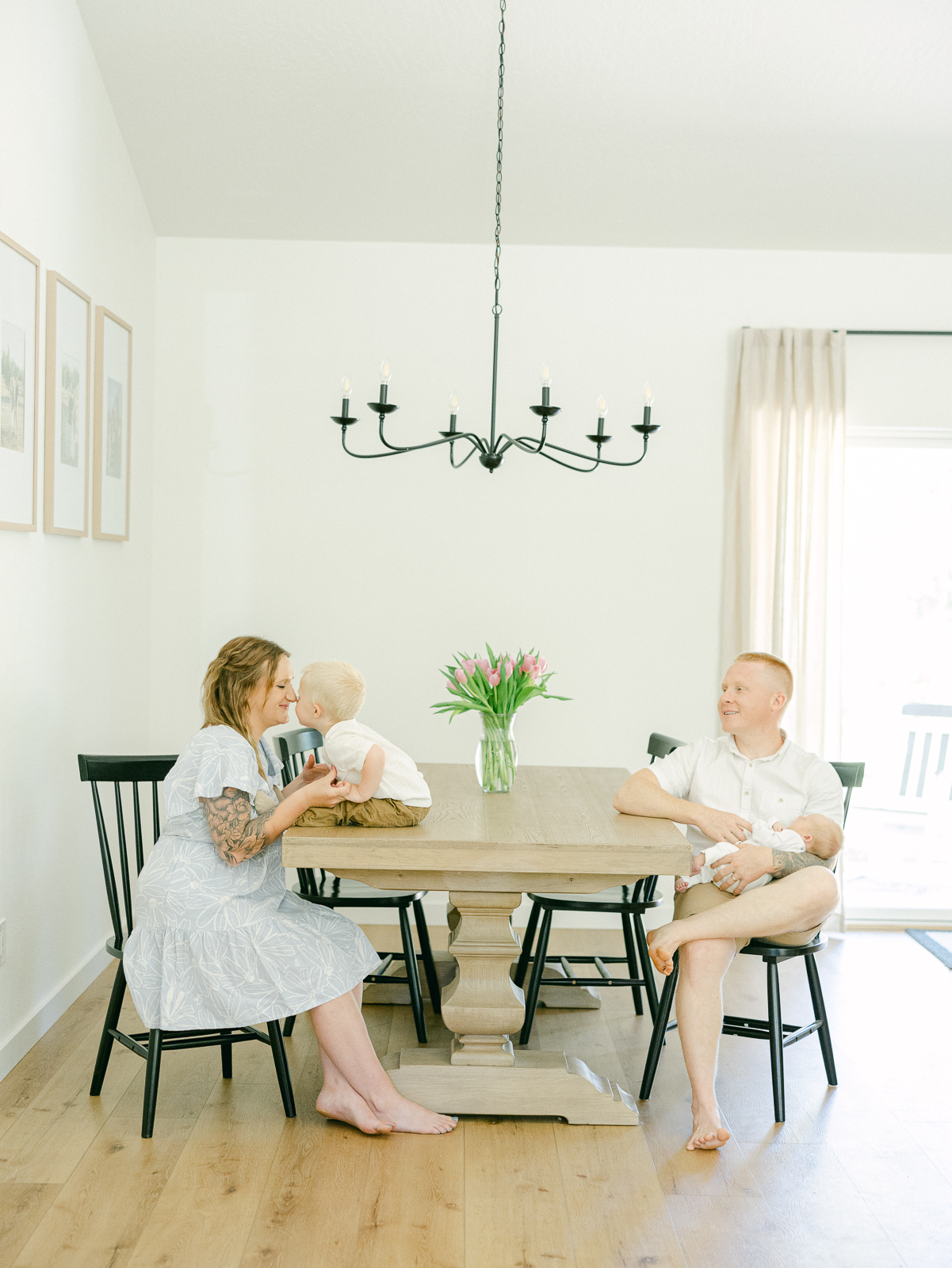 a man and woman sitting at a table with two babies