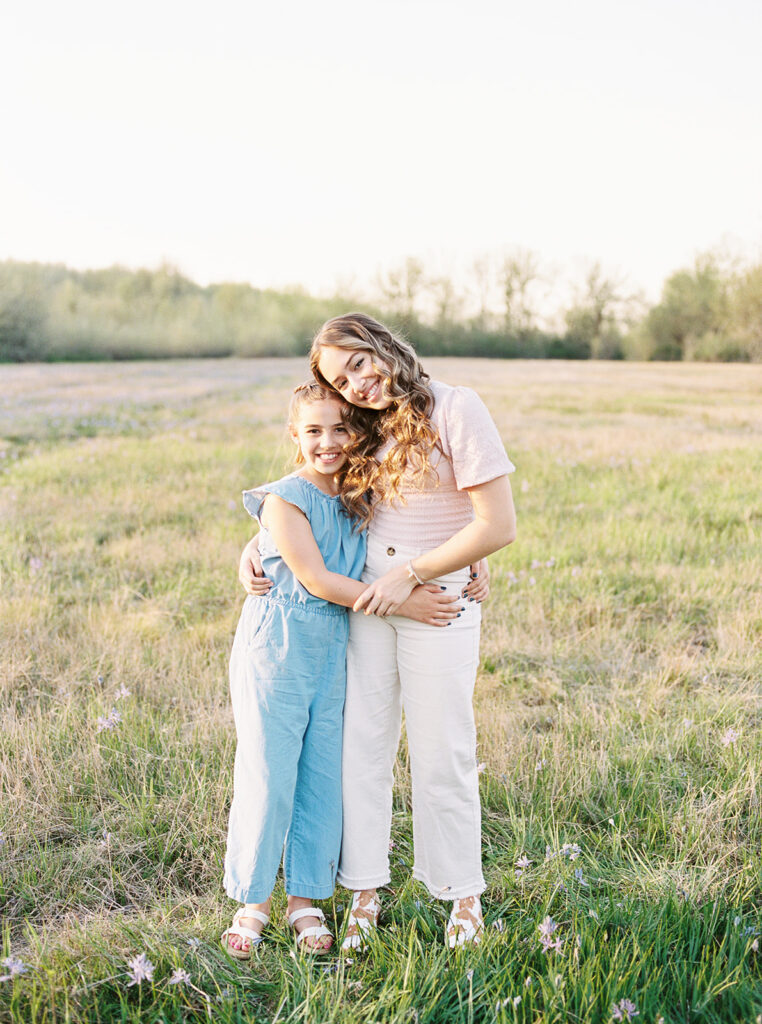 Siblings laughing in a field, dressed in neutral spring colors