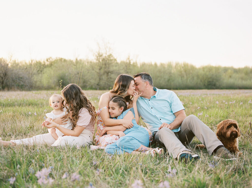 family laughing in a field, dressed in neutral spring colors