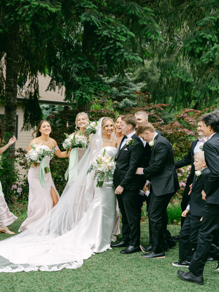 Owen and Emily with their wedding party in blush dresses and black suits at their spring Oregon wedding.