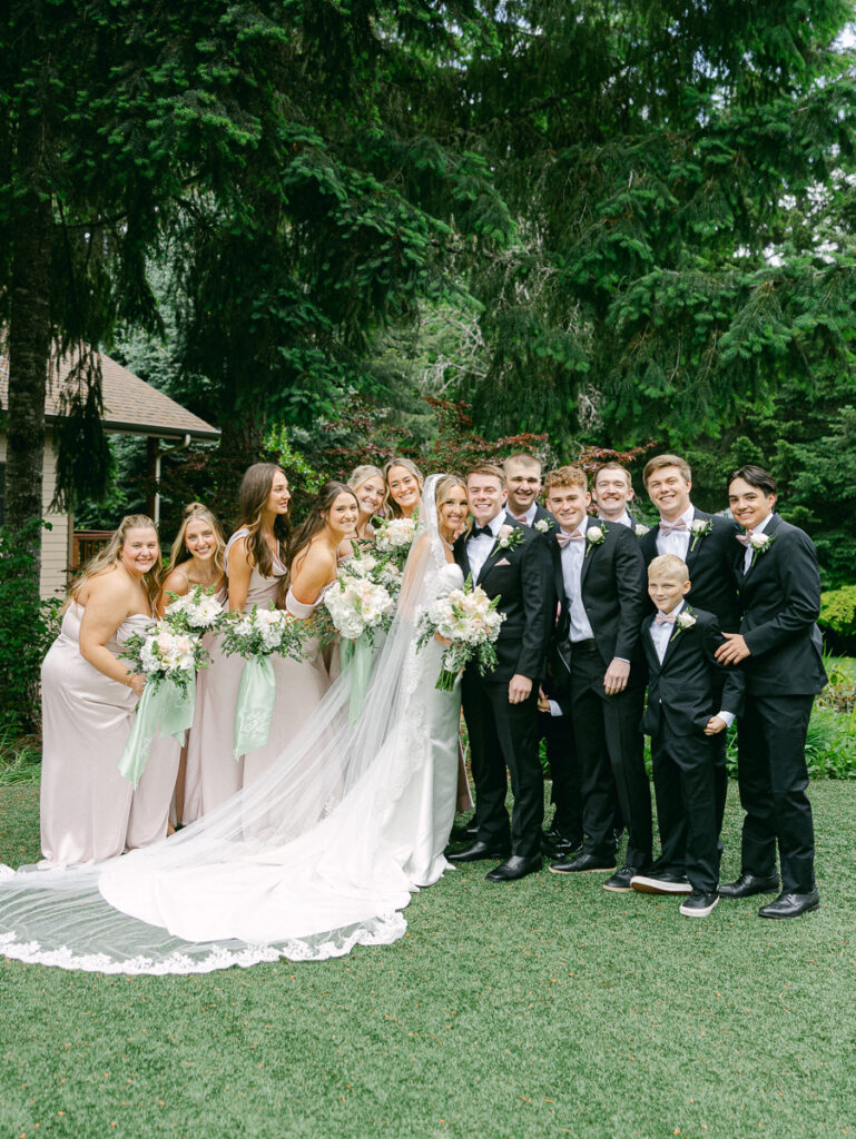 Owen and Emily with their wedding party in blush dresses and black suits at their spring Oregon wedding.