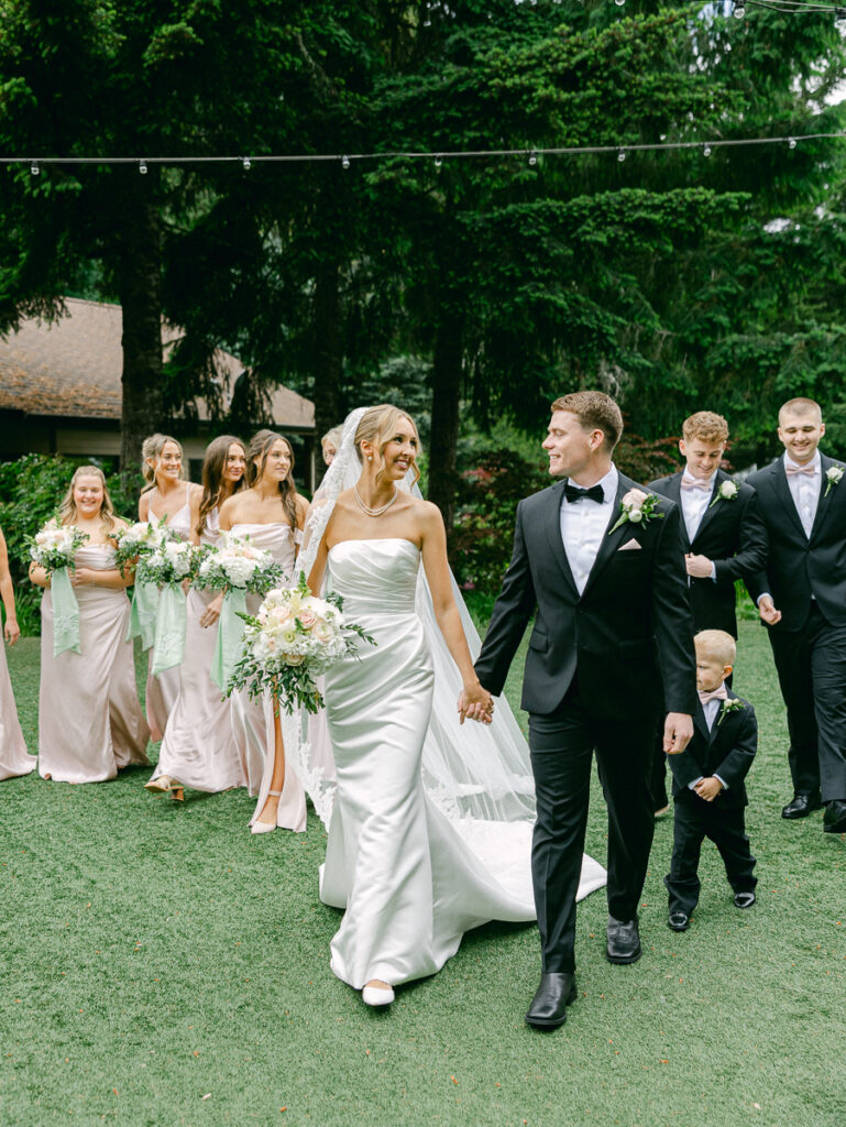 Owen and Emily with their wedding party in blush dresses and black suits at their spring Oregon wedding.
