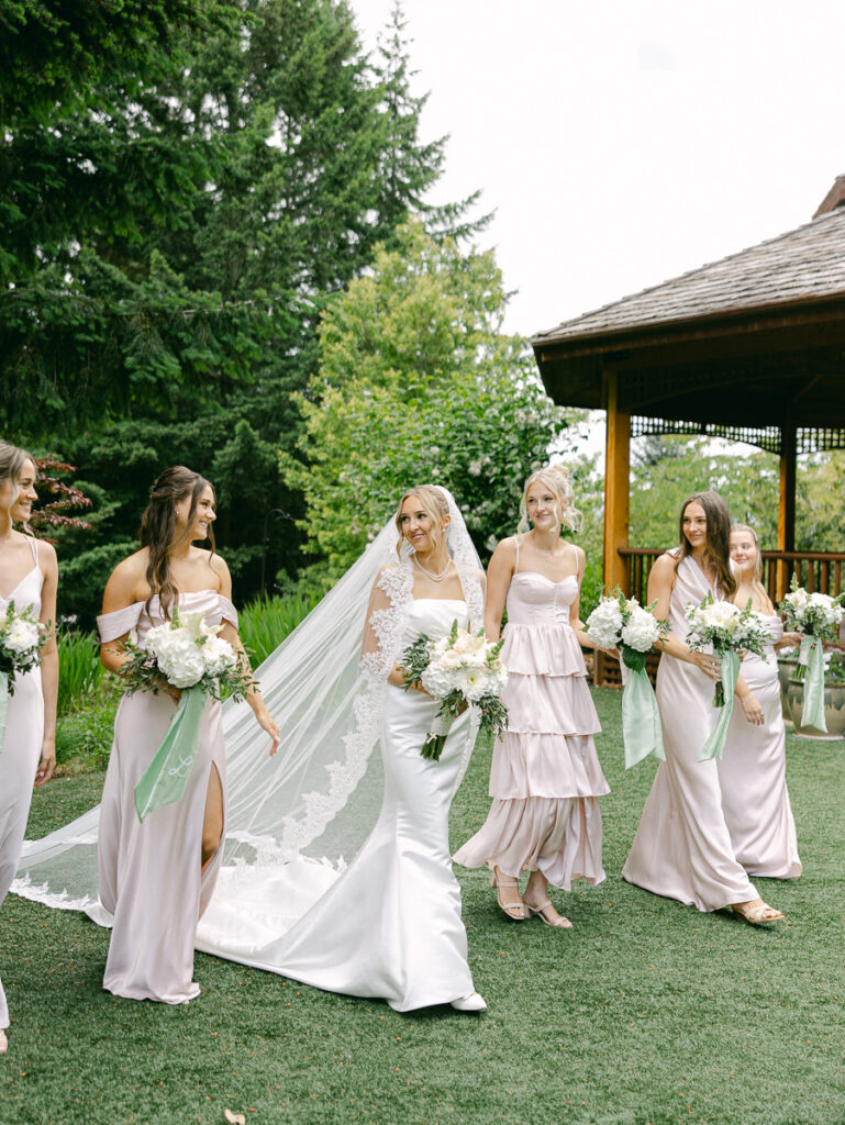Emily with her wedding party in blush dresses and black suits at their spring Oregon wedding.